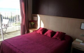 A hotel room with a large bed, a desk, and a view of the outdoors. - Spunta Di Mare (Ajaccio)