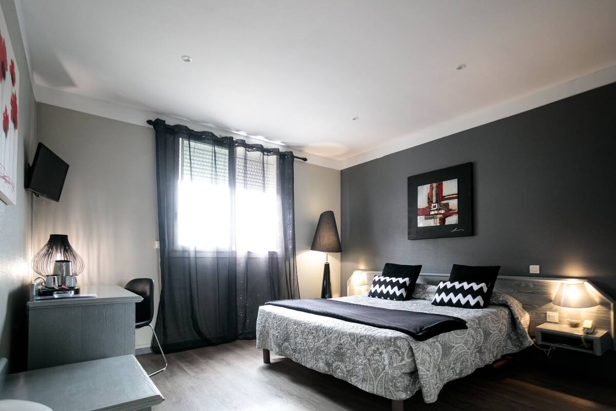 Ein modernes Schlafzimmer mit einem Bett, Nachttischen, einem Schreibtisch und einem Fernseher.