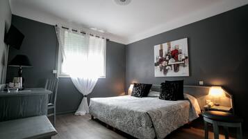 Une chambre à coucher avec un lit, une table de chevet, une lampe, une chaise et un tableau au mur.