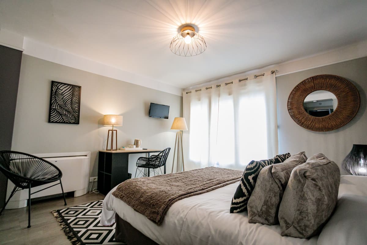 Ein Schlafzimmer mit einem Bett, einem Schreibtisch, einem Stuhl, einem Fernseher und einem großen Spiegel.