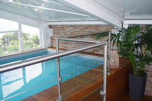 A swimming pool with a glass barrier, wooden flooring, and a brick wall. - Spunta Di Mare (Ajaccio)