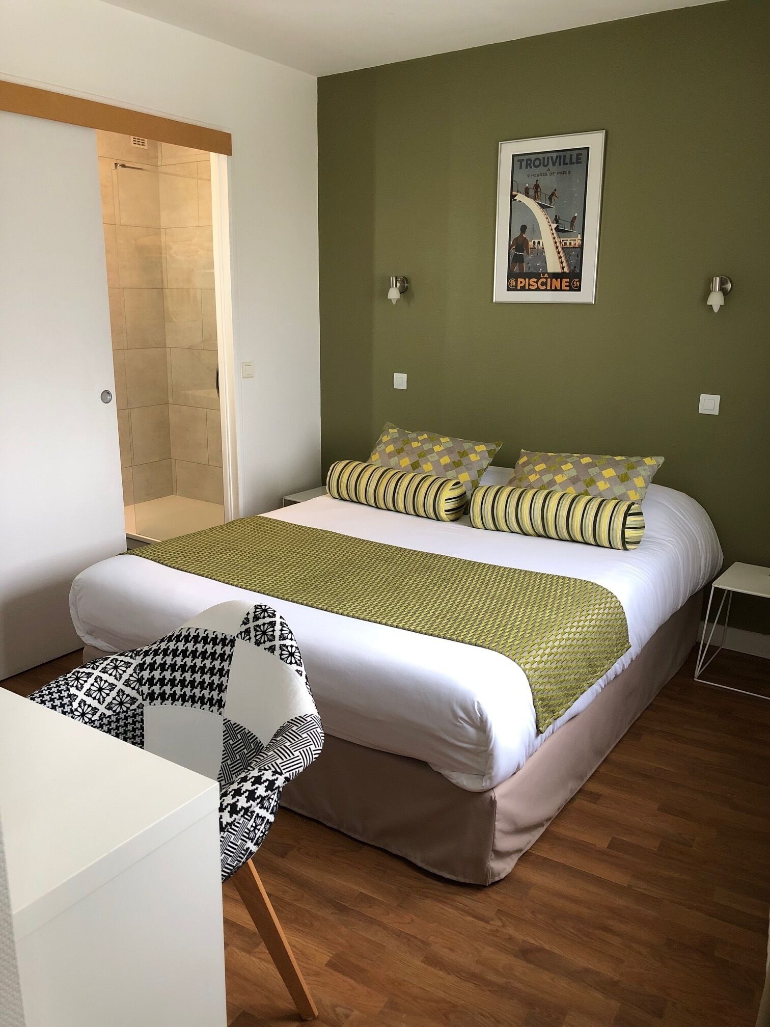 A bedroom with a bed, a chair, a shower, and a poster on the wall.