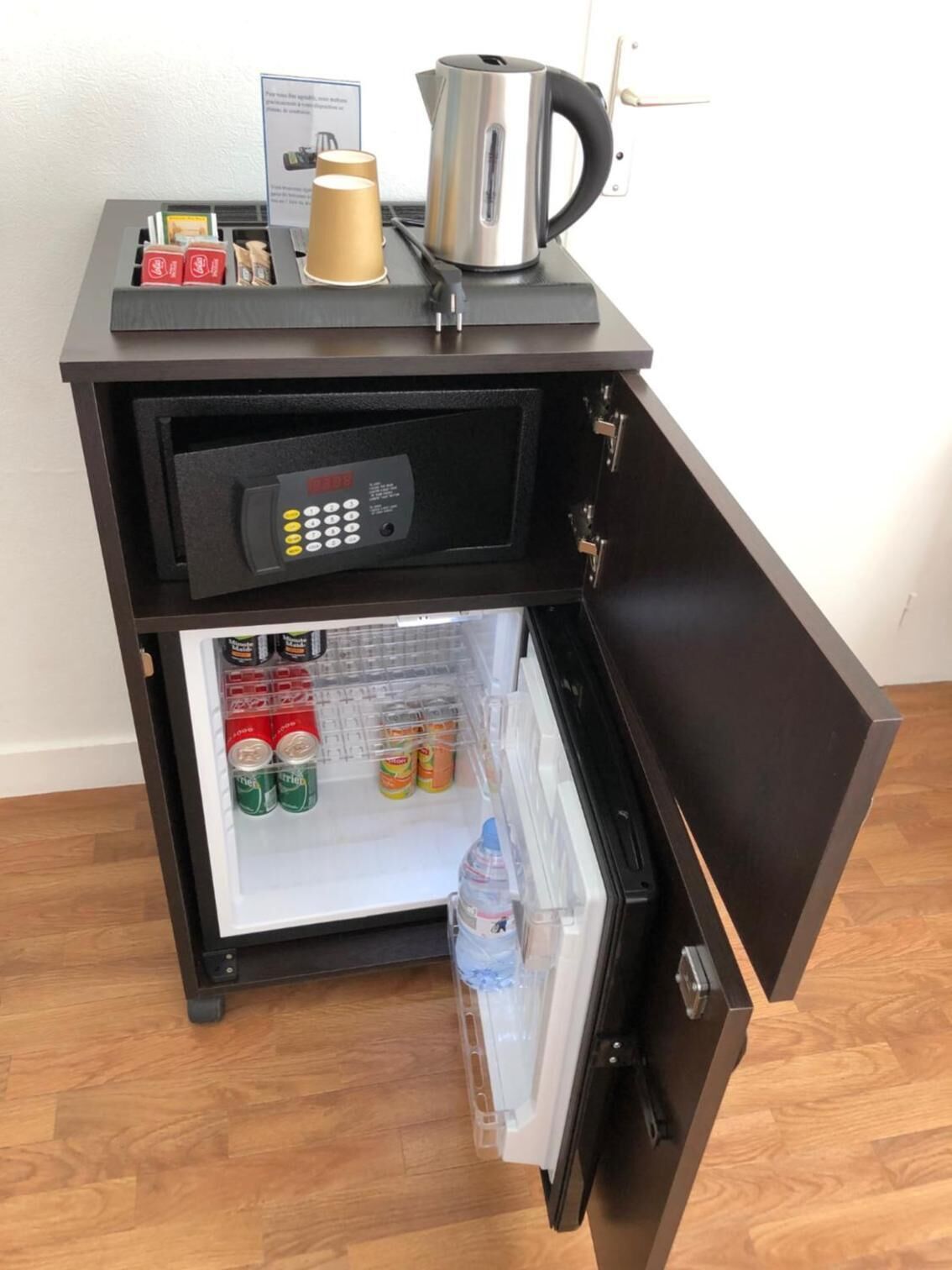 A compact minibar with a coffee maker, a small refrigerator stocked with beverages, and a microwave.