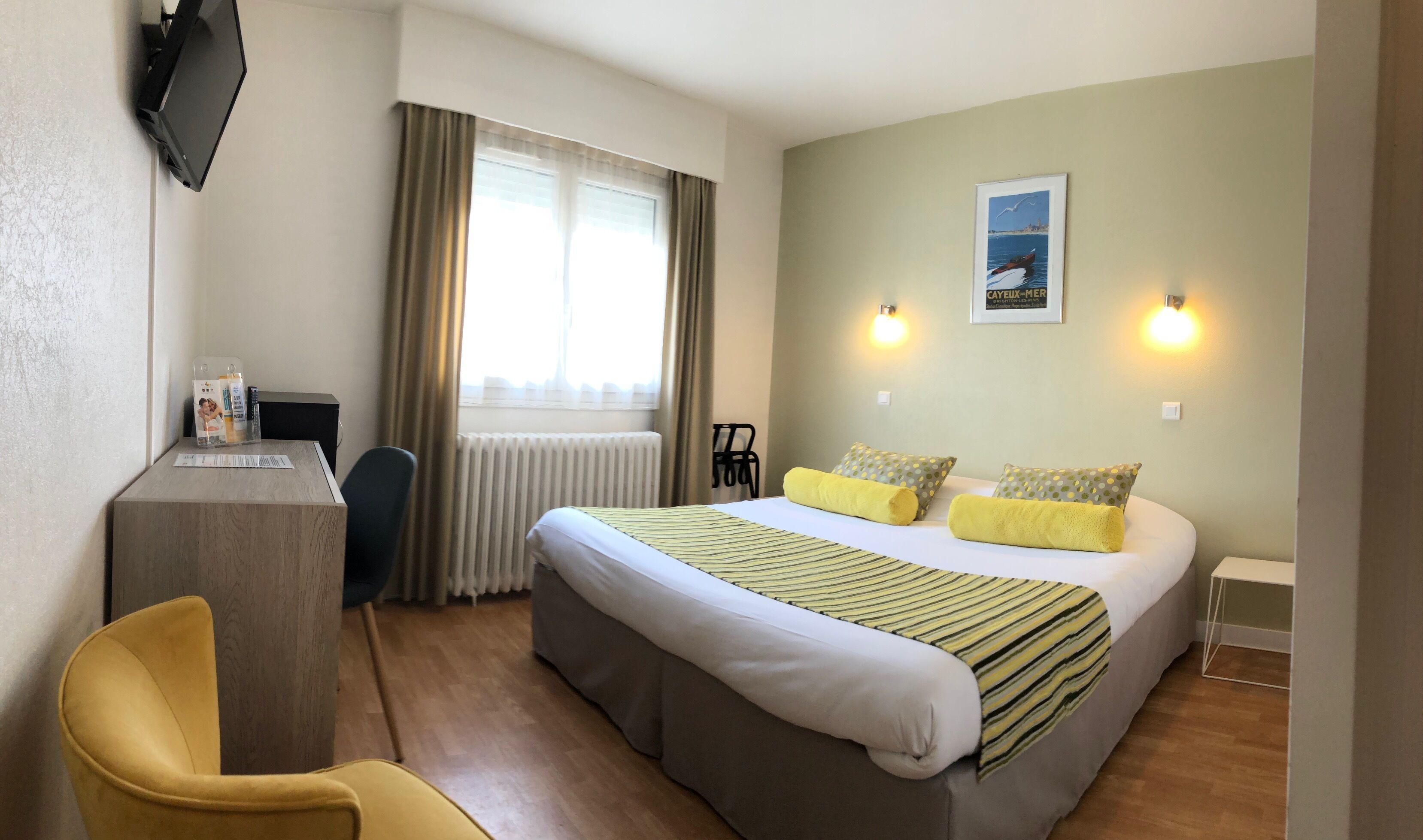 A hotel room with a bed, a desk, a chair, and a window with curtains.