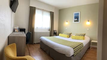 A hotel room with a bed, a desk, a chair, and a window with curtains.