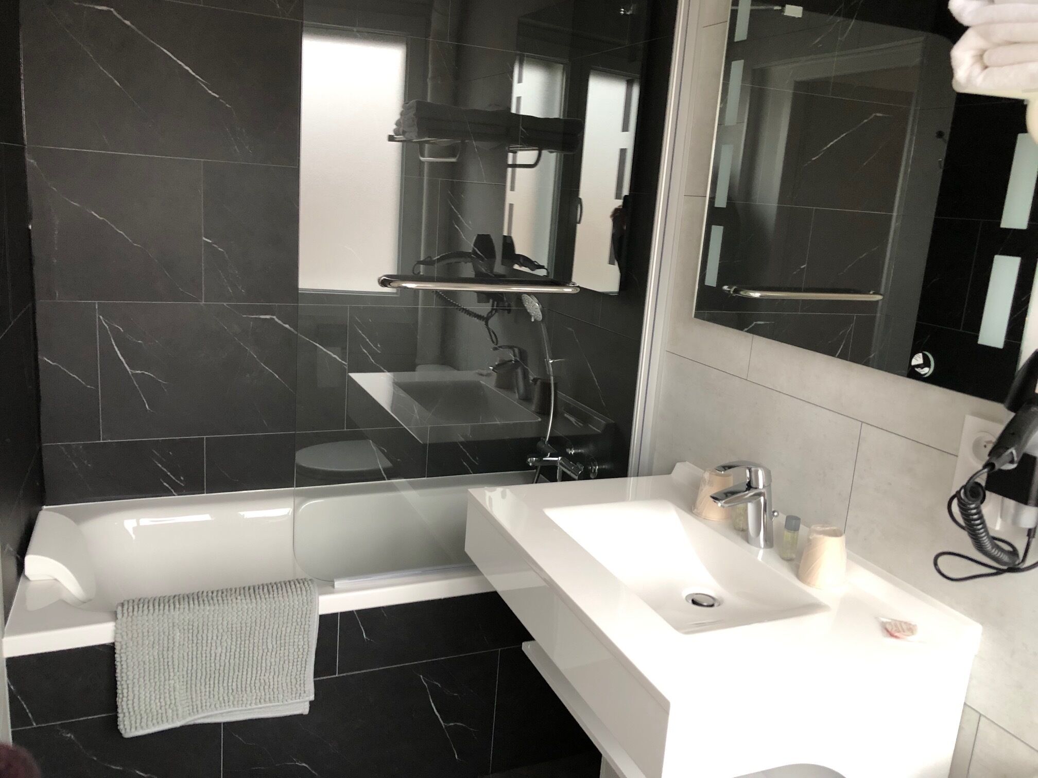 A modern bathroom with a bathtub, a sink, and a large mirror.