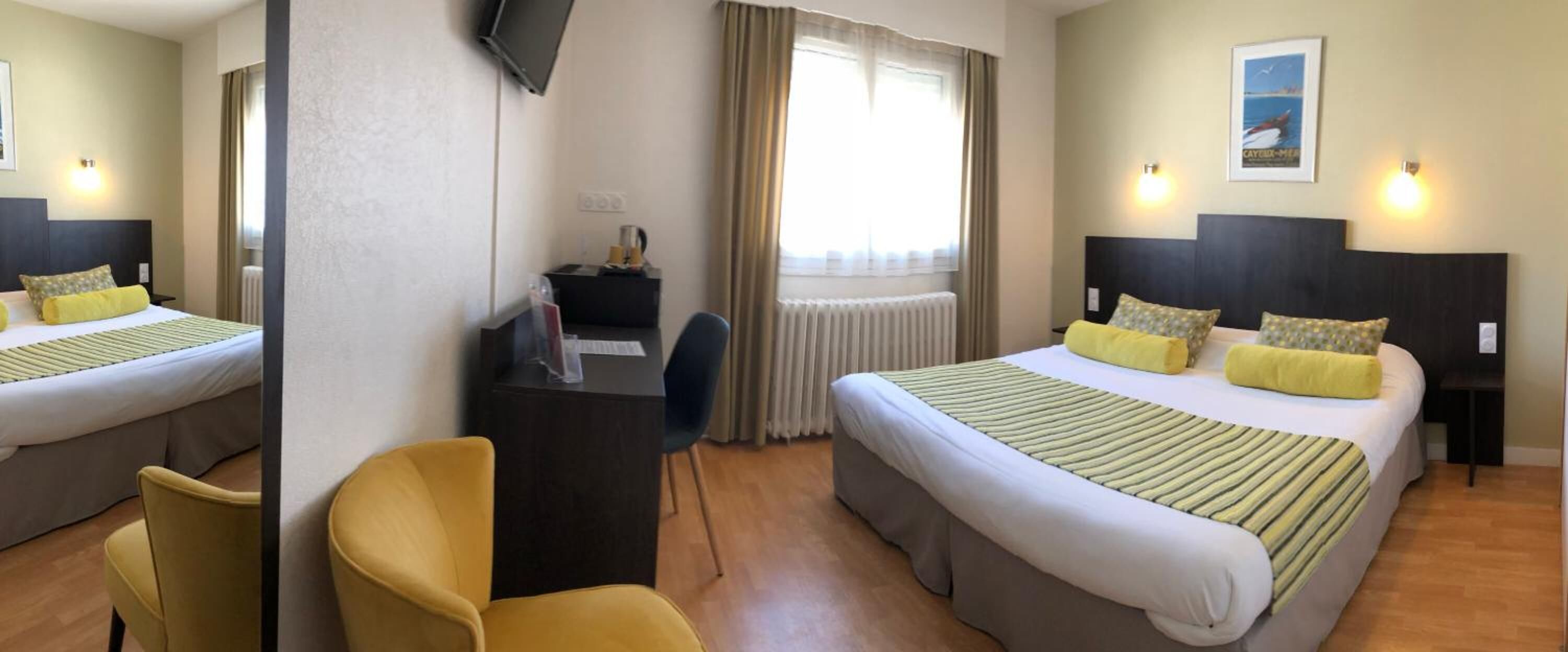 Habitación de hotel con dos camas, un escritorio, una silla, un televisor y una ventana con cortinas.