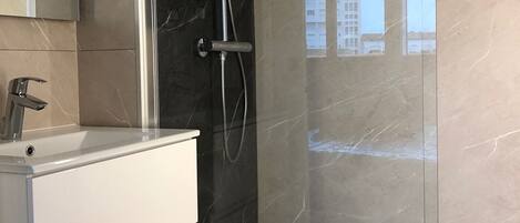A modern bathroom with a glass-enclosed shower, a white vanity, and a large mirror.