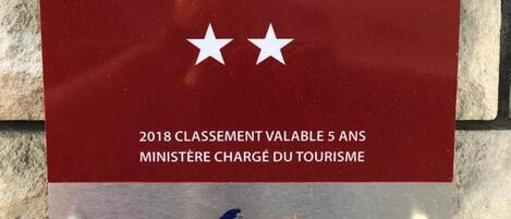 Ein Schild mit einem großen 'H' und zwei Sternen, das ein Hotel kennzeichnet. Auf dem Schild stehen die Aufschriften '2018 Classement Valable 5 Ans' und 'Ministère Charge Du Tourisme'.