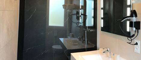 A modern bathroom with a glass shower enclosure, a white sink, and a large mirror.