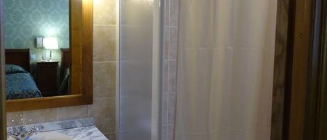 A bathroom with a shower, a sink, and a mirror.