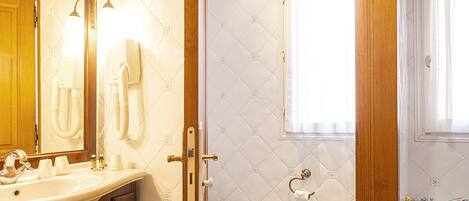 A bathroom with a checkered floor, a sink with a mirror, a toilet, and a bathtub.