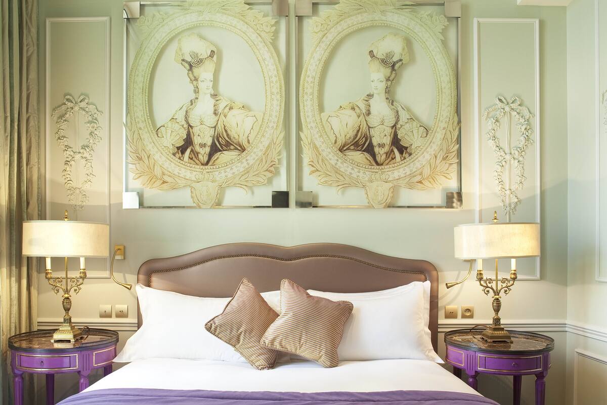A bed with two pillows, two bedside tables, and two wall-mounted lamps.