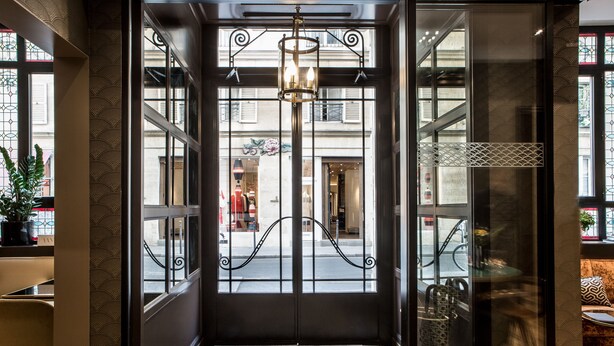 L'ingresso di un hotel con un tappetino decorativo, un lampadario e vista sulla strada.