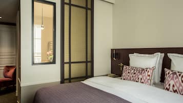 Una habitación de hotel con una cama grande, un armario, una silla y un biombo decorativo.