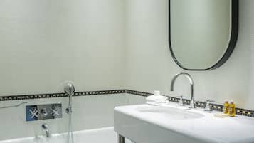 A modern bathroom with a white sink, a large mirror, and a bathtub.