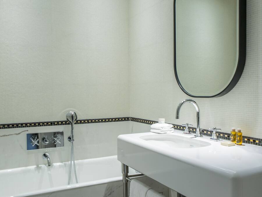 A modern bathroom with a white sink, a large mirror, and a bathtub.