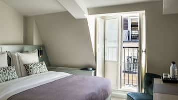 A hotel room with a large bed, a desk, a chair, and a balcony with a view.