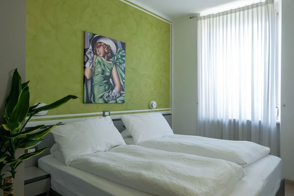 A bedroom with a bed, green wall, and a painting.