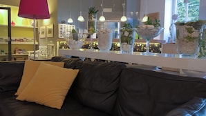 A modern living room with a black leather sofa, a red lamp, and decorative glass vases with plants. - Liberty (Levico Terme)