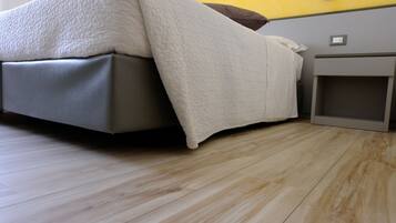 A bed with a white cover, a bedside table, and a small cabinet.