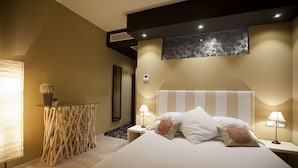 A modern hotel room with a large bed, bedside lamps, a small table with a vase, and a decorative wall piece. - Liberty (Levico Terme)
