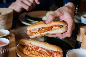 A person holding a sandwich with visible fillings. - Brit Privilège Victoria Boutique Hotel (Saint-Paul-Trois-Chateaux)