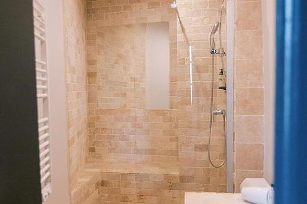 Chuveiro com porta de vidro, porta-toalhas e vaso sanitário branco.