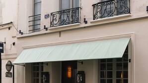 Un edificio con un toldo verde, un balcón de hierro forjado negro y un letrero que dice 