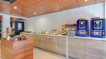 A modern kitchen with wooden cabinets, a breakfast bar, and coffee machines.
