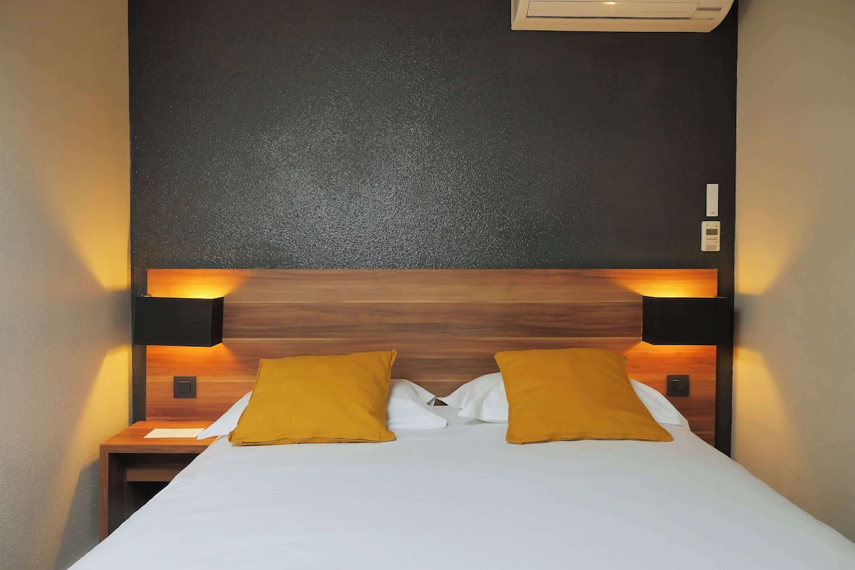 A neatly made bed with two yellow pillows, a wooden headboard, and two bedside lamps.