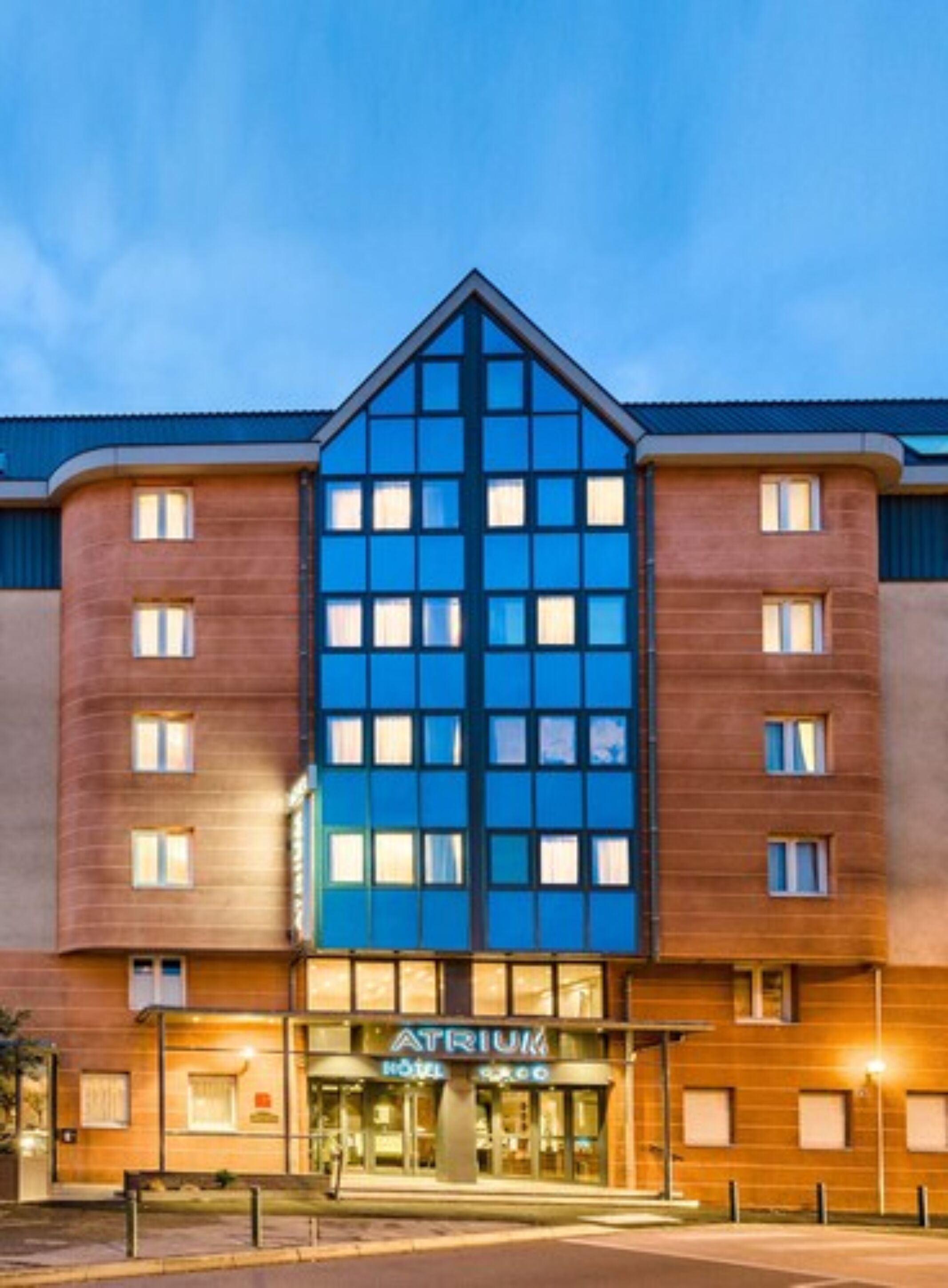 A hotel with a modern design, featuring a prominent blue glass facade and a traditional brick exterior.