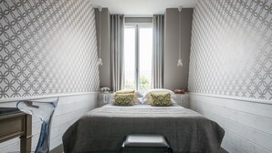 Una camera da letto con un letto, due cuscini, una sedia e una finestra con tende.