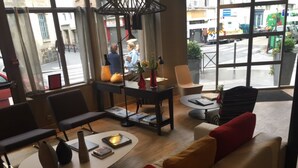 Un ambiente moderno con un divano, poltrone, un tavolino da caffè e un piccolo tavolo con libri e una lampada.