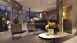 Una hall moderna con reception, area salotto e ampie finestre.