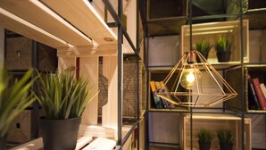 A modern interior with wooden shelves, potted plants, and a geometric light fixture. - Hostal The Good Rooms (Madrid)