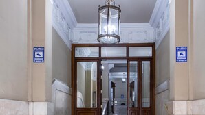 A grand entrance with marble steps, a chandelier, and a sign indicating a location. - Hostal The Good Rooms (Madrid)