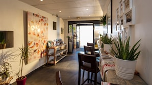 A spacious indoor area with a long table, chairs, and potted plants. - Splendid Hôtel Camargue (Le Grau-Du-Roi)