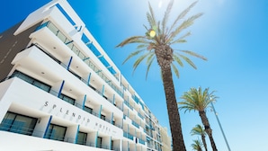 A modern hotel with multiple balconies and a clear view of palm trees. - Splendid Hôtel Camargue (Le Grau-Du-Roi)