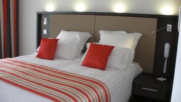 Une chambre d’hôtel avec un lit, deux tables de chevet et un téléphone.
