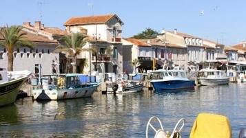 Un port où des bateaux sont amarrés, un ciel dégagé et des bâtiments en arrière-plan.