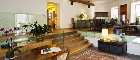 Amplia sala de estar con una escalera de madera, una mesa de comedor con sillas, un sofá y una mesa de centro.