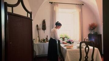 Una habitación con una mesa de comedor para dos personas, una ventana con cortinas y una puerta con marco de madera.