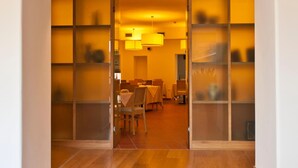 An interior view of a hallway leading to a dining area with a wooden floor and a glass partition. - Romanda (Levico Terme)