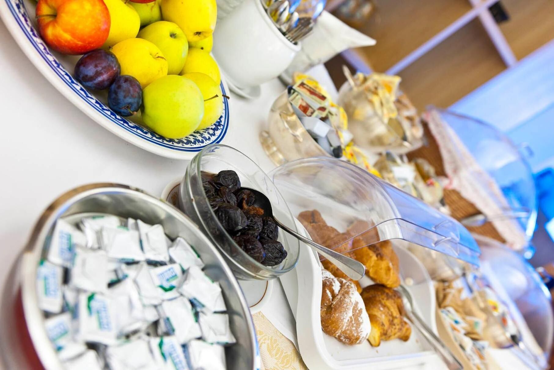 A buffet with various food items including fruits, pastries, and packaged snacks.