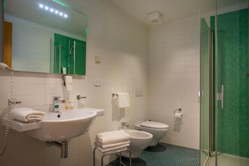 A modern bathroom with a sink, toilet, bidet, and a glass-enclosed shower area.