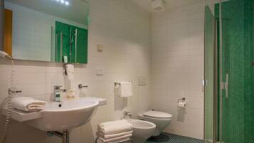 A modern bathroom with a sink, toilet, bidet, and a glass-enclosed shower area.