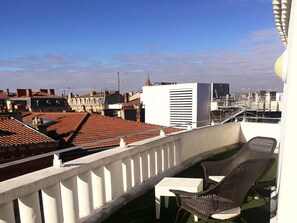 A balcony with a white railing, a small table, and two wicker chairs. - Ours Blanc-Wilson (Toulouse)