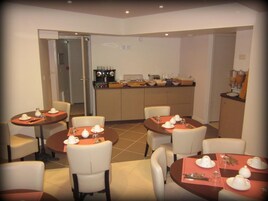 A dining area with tables set for four, each with white tableware and chairs.