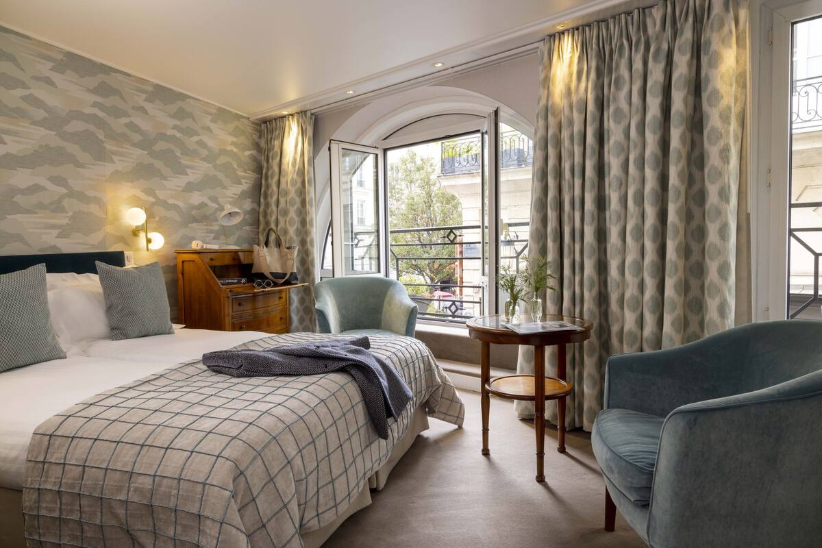 Une chambre d’hôtel avec un grand lit, un bureau, une chaise et une vue sur le balcon extérieur.